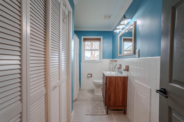 bathroom featuring crown molding, vanity, toilet, and tile walls