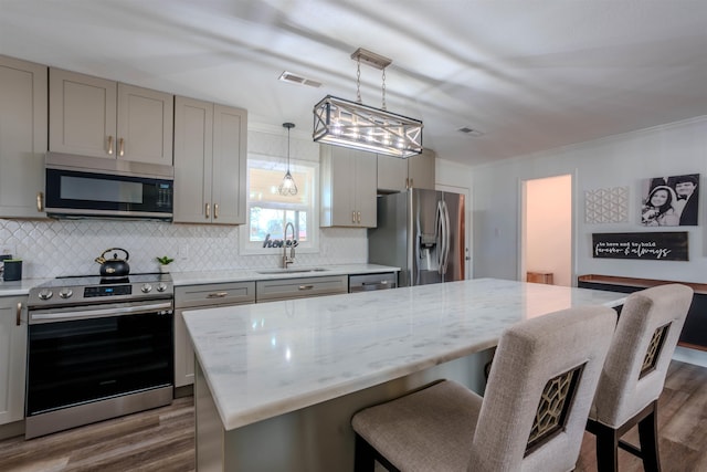 kitchen with light stone counters, appliances with stainless steel finishes, a center island, and hanging light fixtures