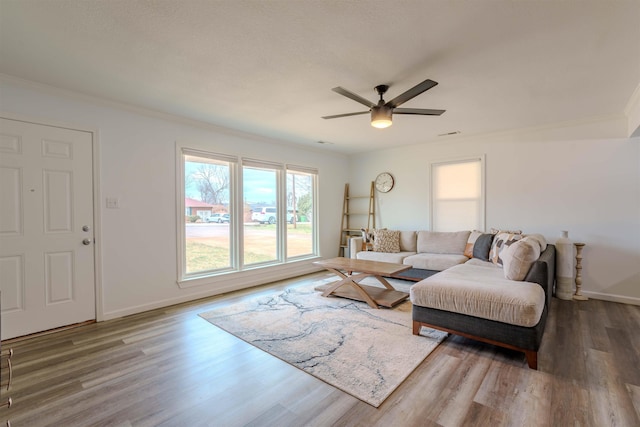 living room featuring crown molding, wood-type flooring, and ceiling fan