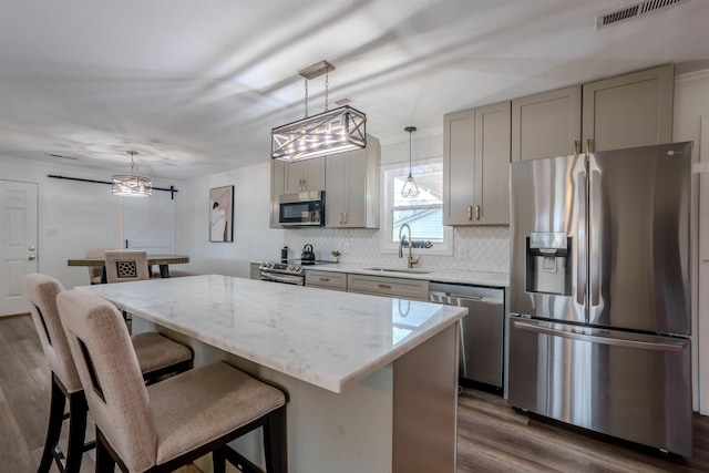 kitchen featuring appliances with stainless steel finishes, gray cabinets, sink, and hanging light fixtures