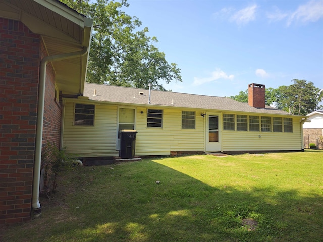  - back of property featuring a chimney, a yard, and roof with shingles
