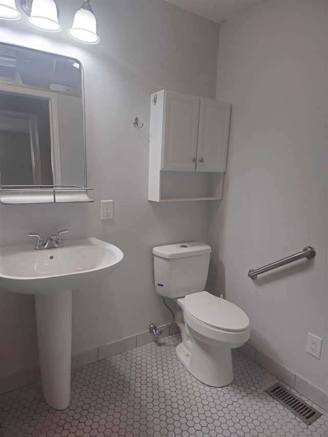  - bathroom with baseboards, toilet, and a sink