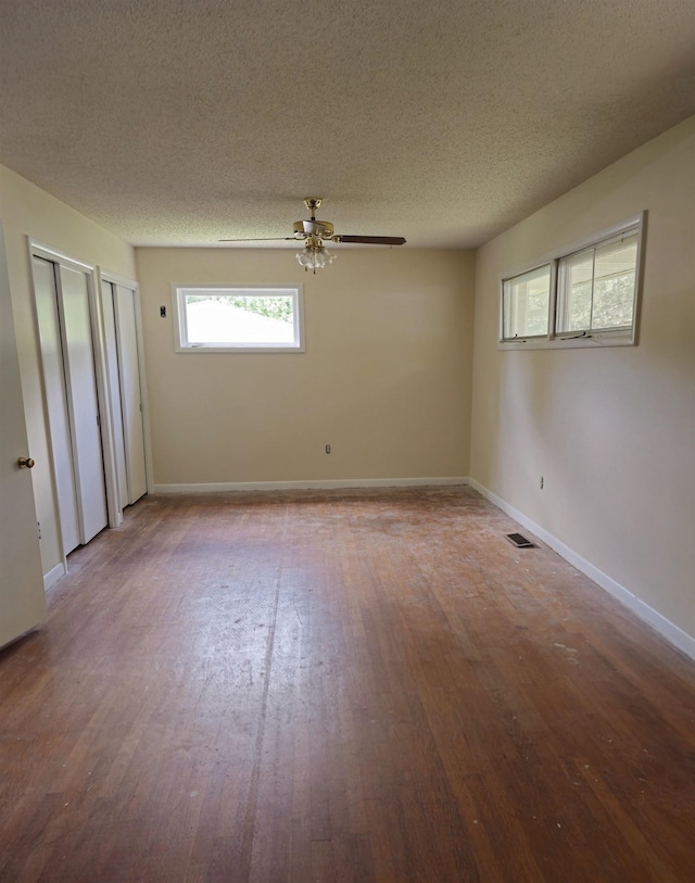  - spare room with ceiling fan, hardwood / wood-style floors, baseboards, and a textured ceiling
