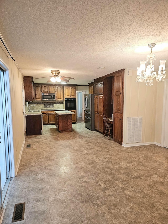  - kitchen featuring stainless steel appliances, a center island, light countertops, a chandelier, and a textured ceiling