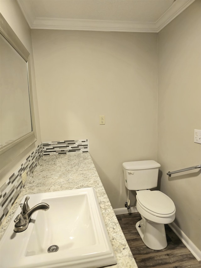  - bathroom featuring crown molding, toilet, wood finished floors, baseboards, and backsplash