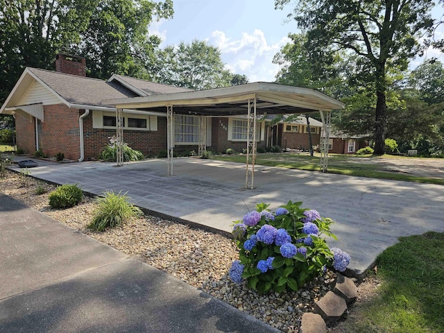  - view of front of property with a chimney, brick siding, and a carport