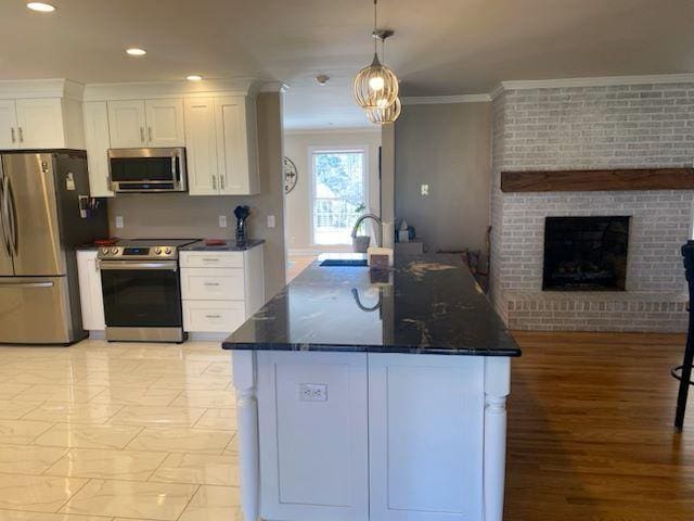  - kitchen with appliances with stainless steel finishes, crown molding, white cabinetry, a fireplace, and recessed lighting