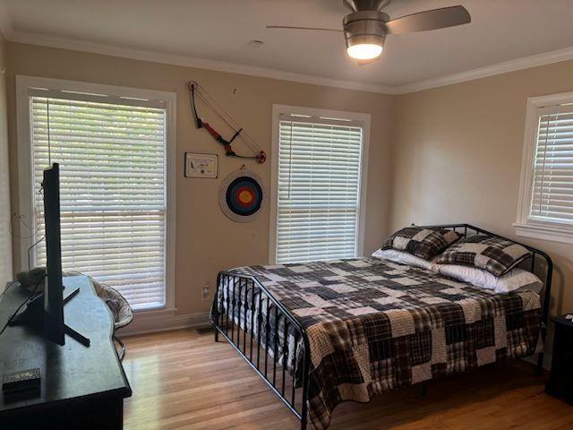  - bedroom with light wood finished floors, ornamental molding, and a ceiling fan