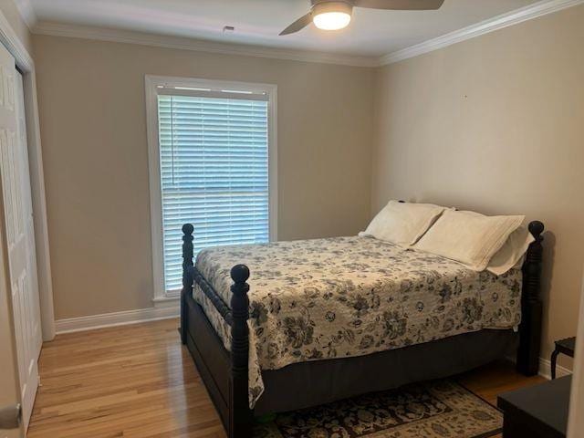  - bedroom featuring light wood-type flooring, ornamental molding, and ceiling fan