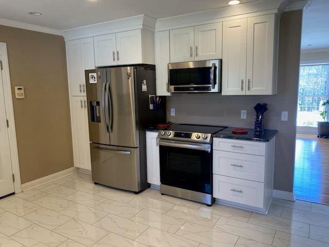 - kitchen featuring appliances with stainless steel finishes, crown molding, white cabinetry, light marble finish floors, and recessed lighting