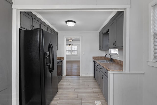 kitchen featuring black fridge, ornamental molding, gray cabinets, and sink