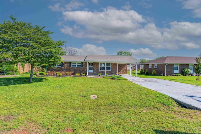 single story home featuring concrete driveway, a carport, a front yard, and brick siding
