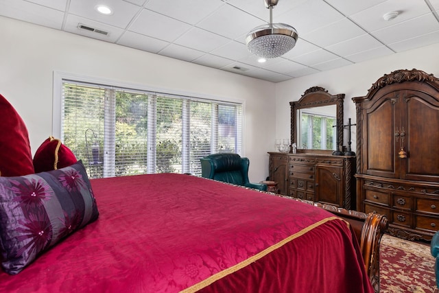 bedroom with a drop ceiling and multiple windows