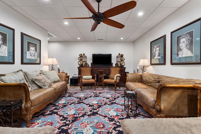 living room with ceiling fan and a drop ceiling