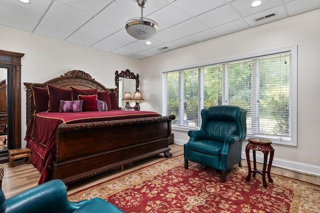 bedroom with a paneled ceiling and hardwood / wood-style floors