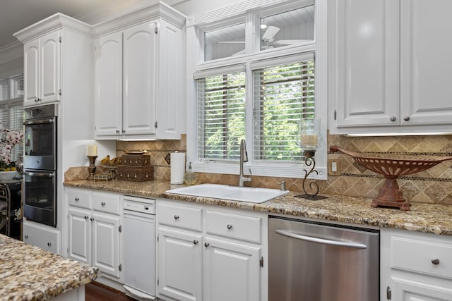 kitchen with light stone countertops, appliances with stainless steel finishes, decorative backsplash, sink, and white cabinetry