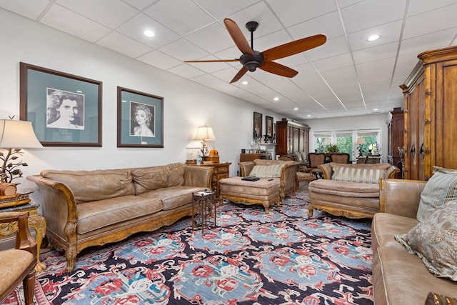 living room with a paneled ceiling and ceiling fan