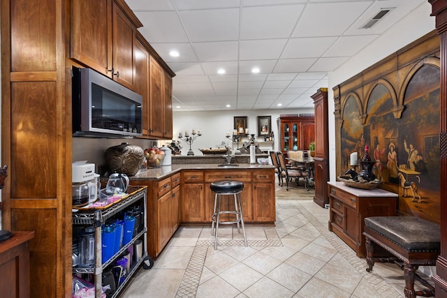 kitchen with kitchen peninsula, a paneled ceiling, and light tile patterned floors