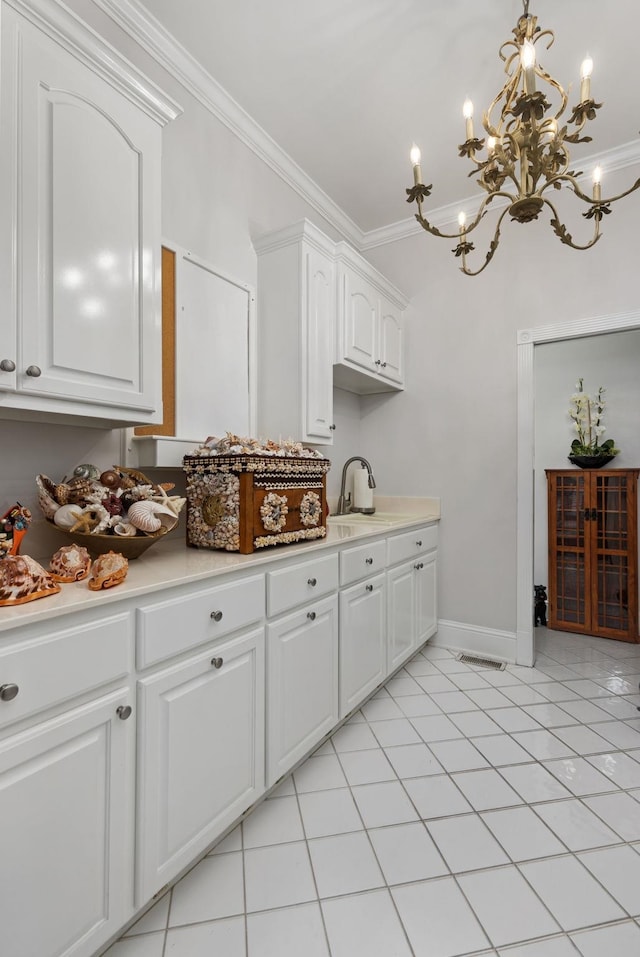 kitchen with an inviting chandelier, white cabinets, sink, crown molding, and light tile patterned floors