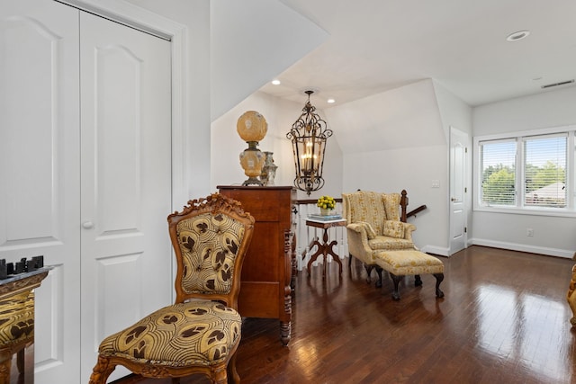 sitting room featuring dark wood-type flooring, lofted ceiling, and an inviting chandelier