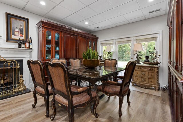 dining area featuring a drop ceiling and light hardwood / wood-style flooring