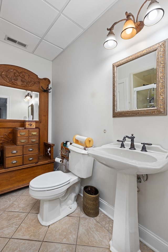 bathroom featuring tile patterned floors, a drop ceiling, toilet, and sink