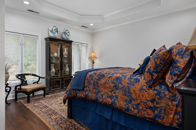 bedroom featuring a raised ceiling, multiple windows, dark hardwood / wood-style floors, and ornamental molding