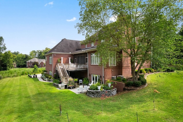 back of property featuring a yard, a sunroom, a patio area, and a wooden deck