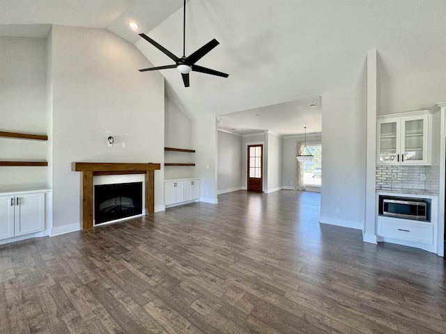 unfurnished living room featuring vaulted ceiling, ceiling fan, and dark wood-type flooring