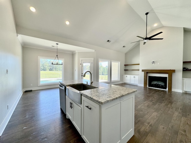 kitchen featuring light stone countertops, sink, decorative light fixtures, a center island with sink, and white cabinetry