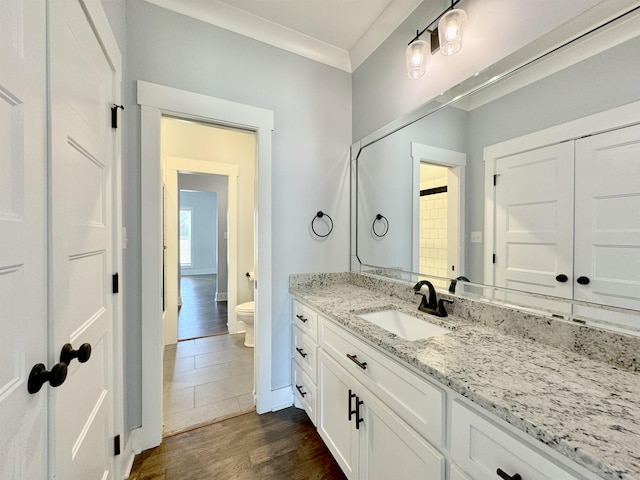 bathroom with toilet, hardwood / wood-style floors, vanity, and ornamental molding