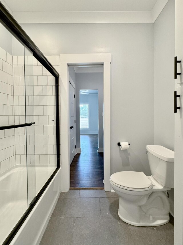 bathroom with crown molding, enclosed tub / shower combo, and toilet