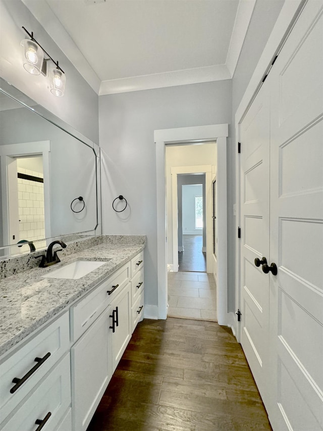 bathroom with crown molding, vanity, and hardwood / wood-style flooring