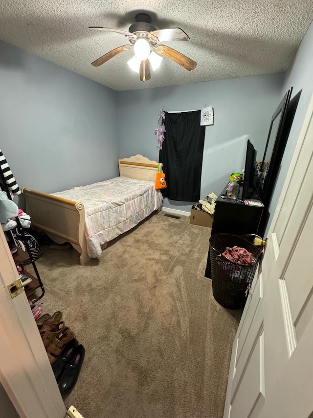 carpeted bedroom featuring a textured ceiling and ceiling fan