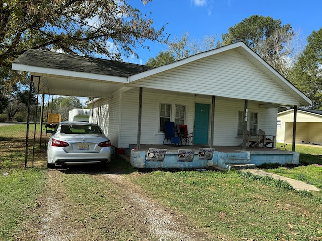 view of front of house featuring covered porch, a carport, and a front lawn