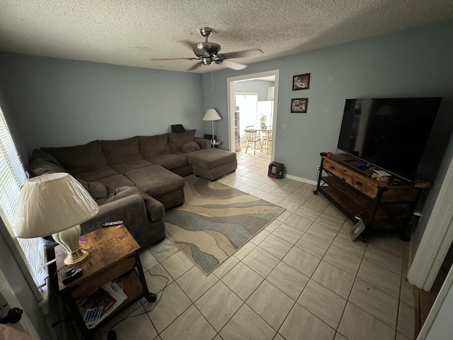 living room featuring ceiling fan, light tile patterned floors, and a textured ceiling