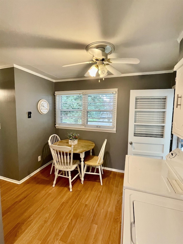 dining room with a ceiling fan, ornamental molding, light wood-style flooring, baseboards, and washing machine and clothes dryer