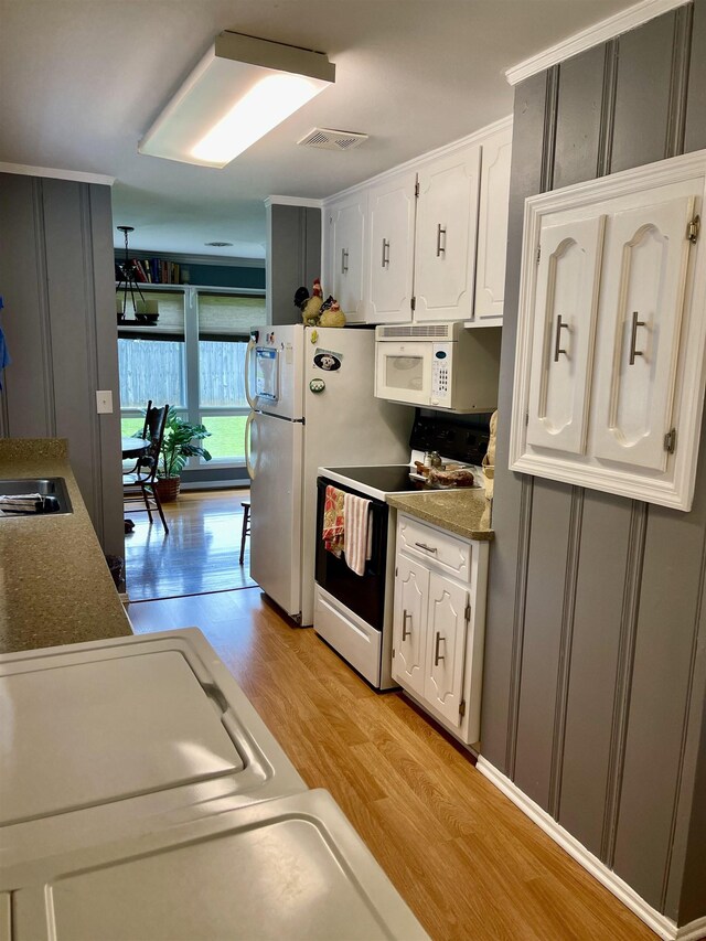 kitchen featuring washer and dryer, a sink, white cabinets, ceiling fan, and light wood finished floors