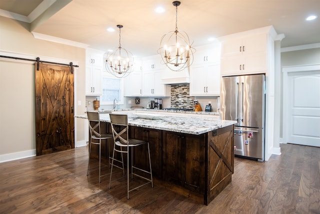 kitchen with a barn door, white cabinetry, appliances with stainless steel finishes, and a center island