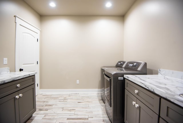 laundry area with cabinets, washer and dryer, and light wood-type flooring