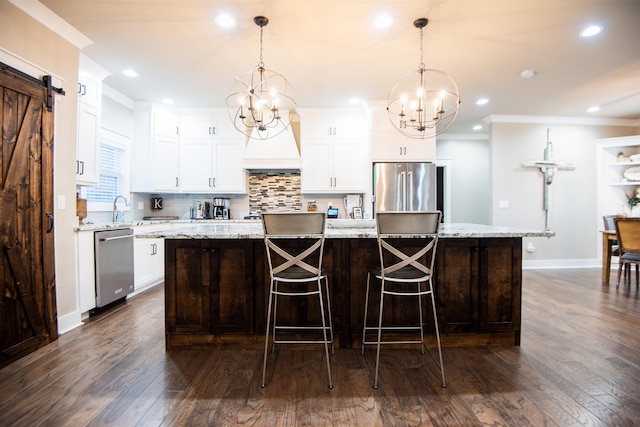 kitchen featuring a barn door, appliances with stainless steel finishes, a center island, and decorative light fixtures