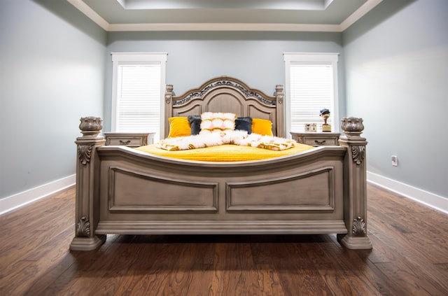 bedroom featuring crown molding, a tray ceiling, and dark wood-type flooring