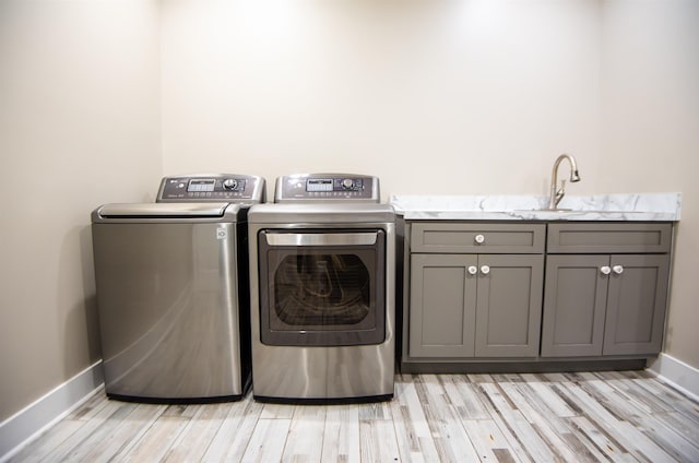 laundry area with cabinets, sink, independent washer and dryer, and light hardwood / wood-style flooring