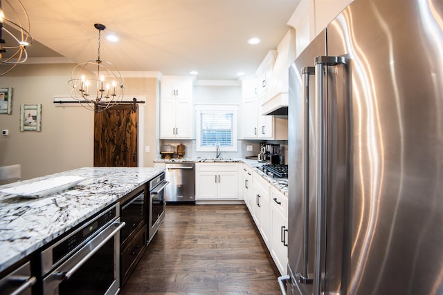 kitchen with decorative light fixtures, sink, white cabinets, stainless steel appliances, and light stone countertops