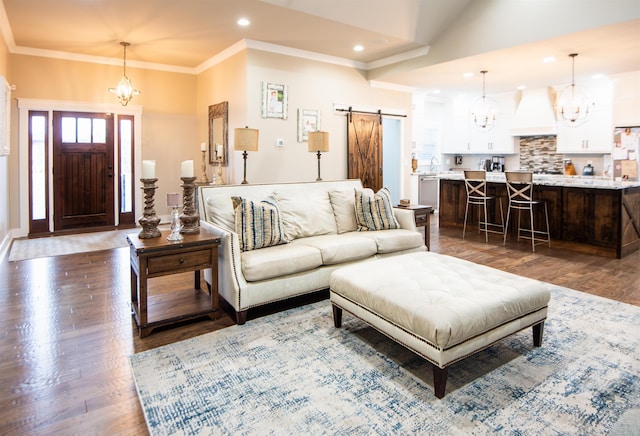 living room with a barn door, dark wood-type flooring, and an inviting chandelier