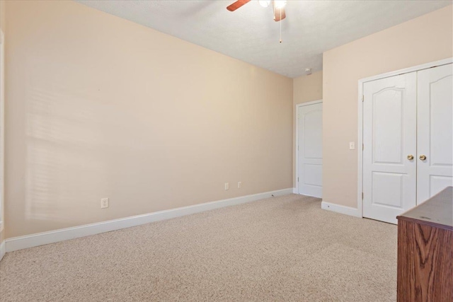 unfurnished bedroom with light colored carpet, baseboards, a ceiling fan, and a closet