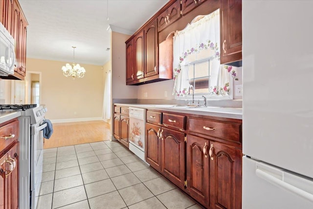 kitchen featuring white appliances, a sink, ornamental molding, light countertops, and a chandelier