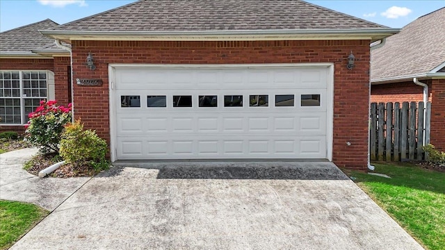 garage featuring concrete driveway and fence