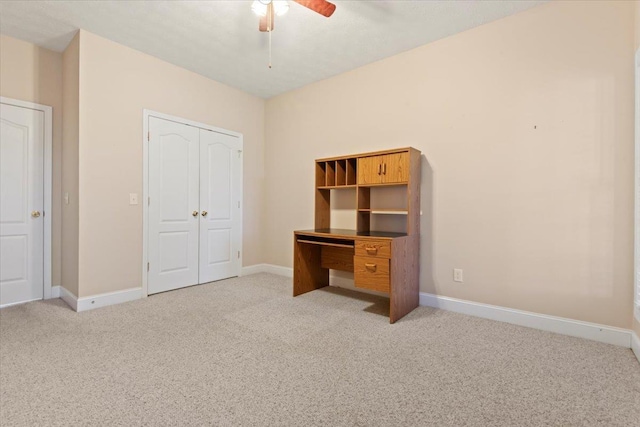 unfurnished office with light carpet, ceiling fan, and baseboards