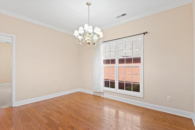 empty room with a chandelier, ornamental molding, baseboards, and light wood-style floors
